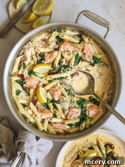 salmon pasta in cream sauce, garnished with fresh herbs and a lemon wedge.