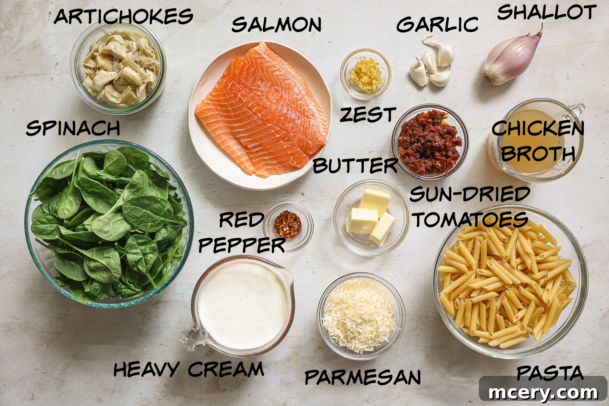 fresh ingredients for salmon pasta, including salmon fillet, penne, heavy cream, spinach, sun-dried tomatoes, and aromatics.