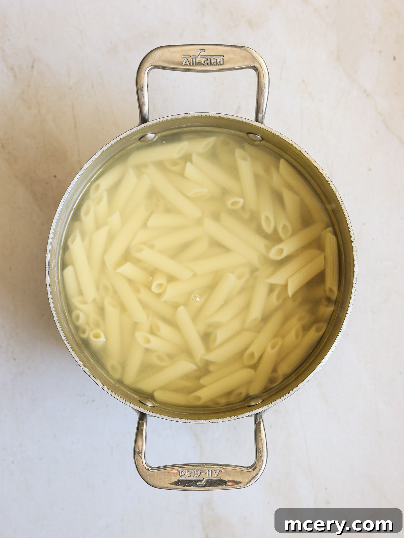 cooked penne pasta in a pot, ready for the sauce.