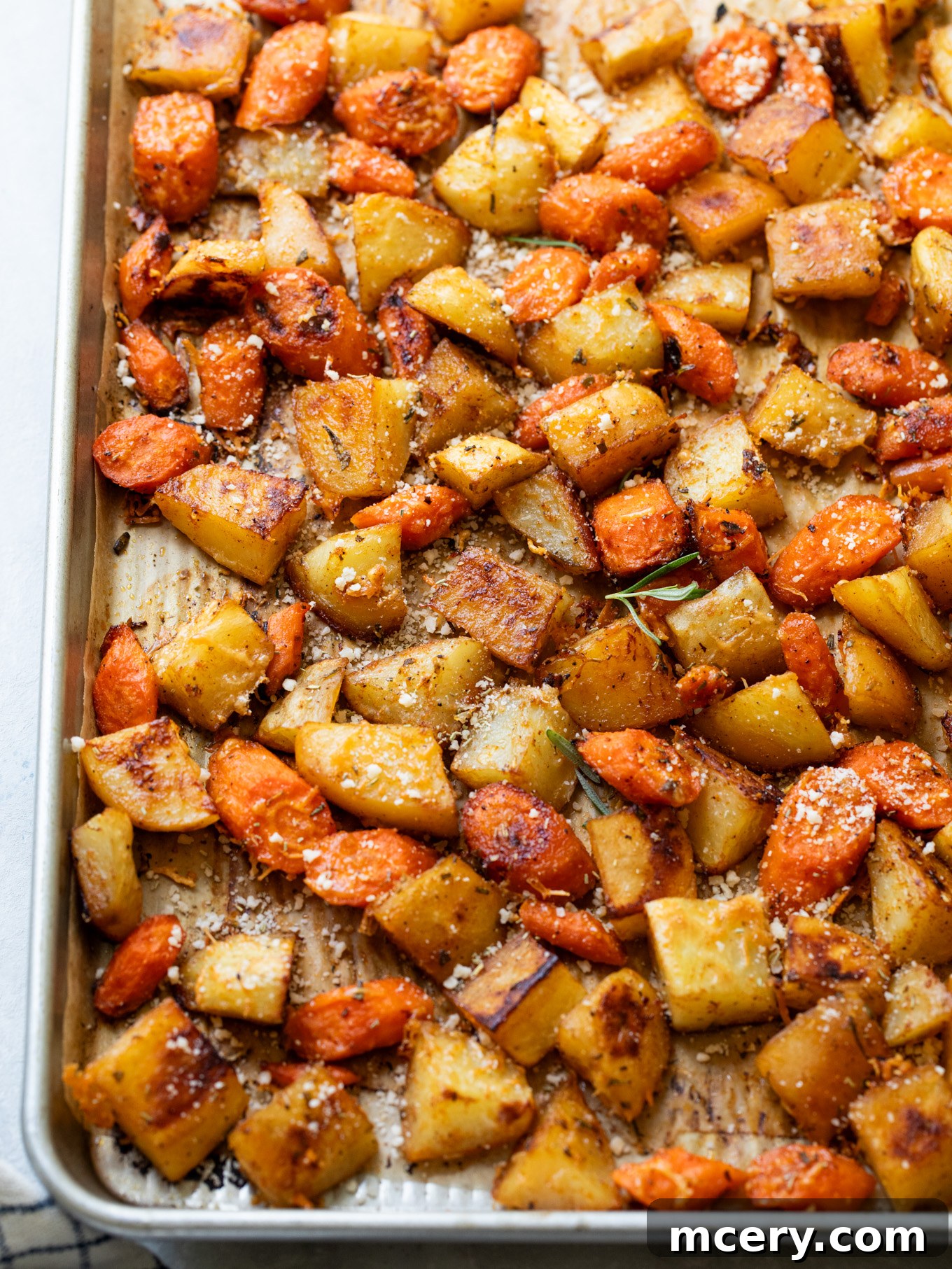 Caramelized Carrots and Crispy Potatoes 8 close up carrots with potatoes on a sheet pan, showing crispy edges and tender centers.