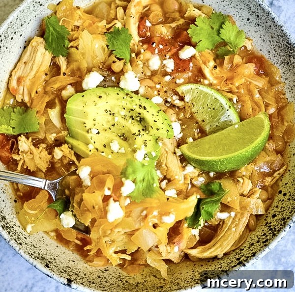 Rustic Chicken, Cabbage, and White Bean Soup 4 A bowl of Cabbage Soup with White Beans and Chicken, topped with fresh cilantro, crumbled cheese, and a lime wedge, highlighting the fresh garnishes.