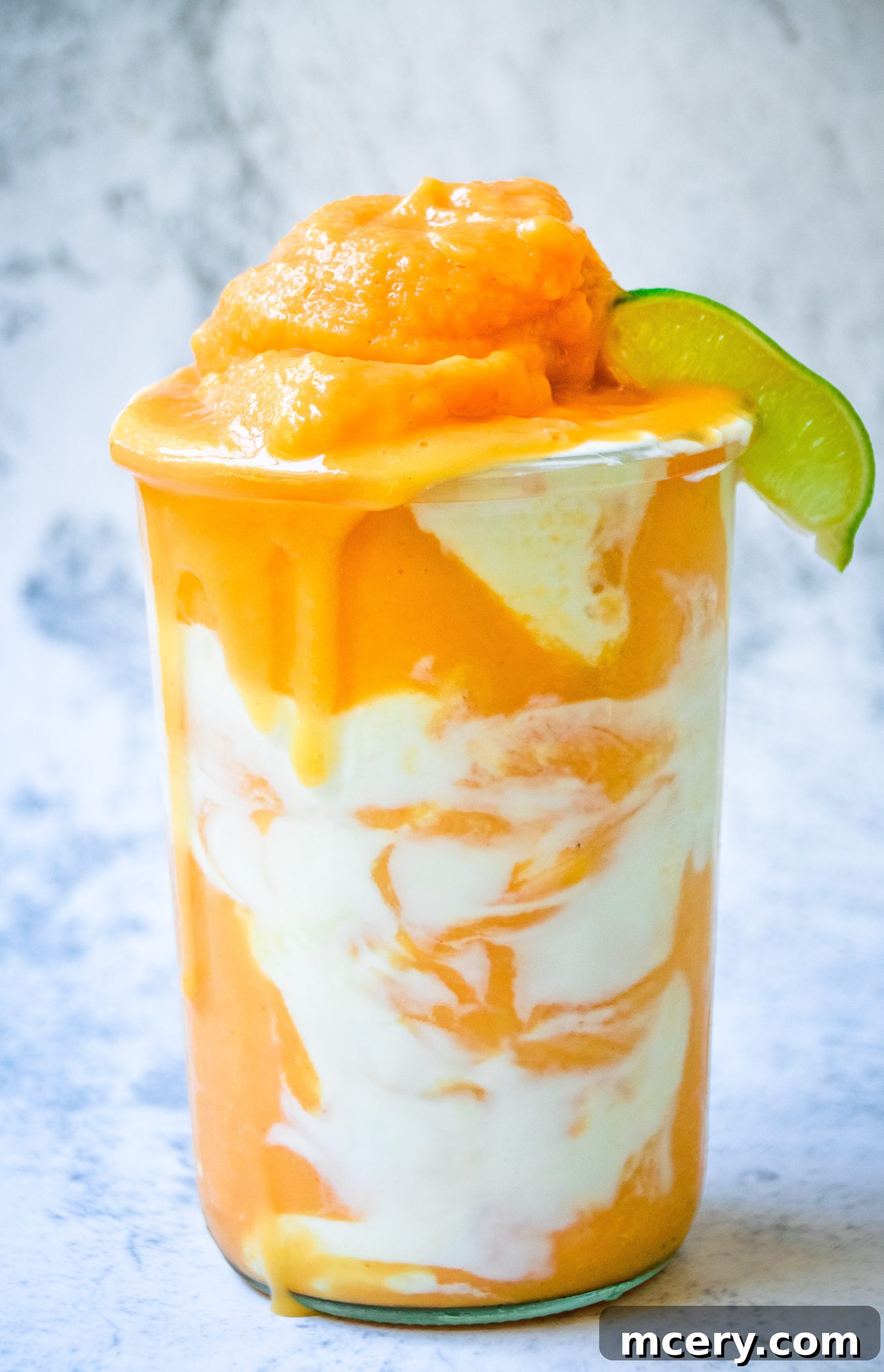 A glass of vibrant orange Papaya Dream Smoothie, garnished with a slice of lime and fresh mint leaves, set against a bright, sunny background.
