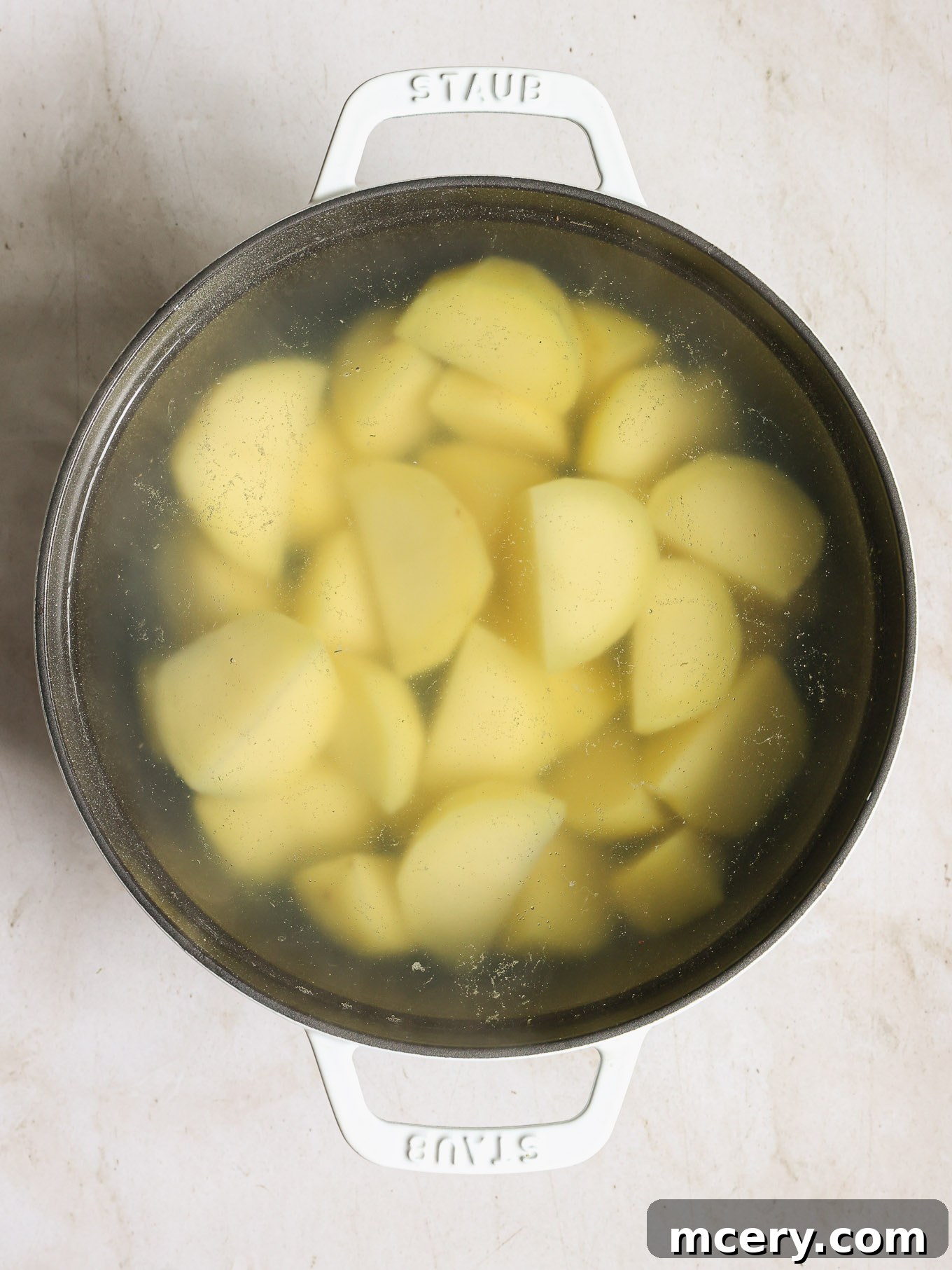 Cubed potatoes boiling in a pot on a stove top.