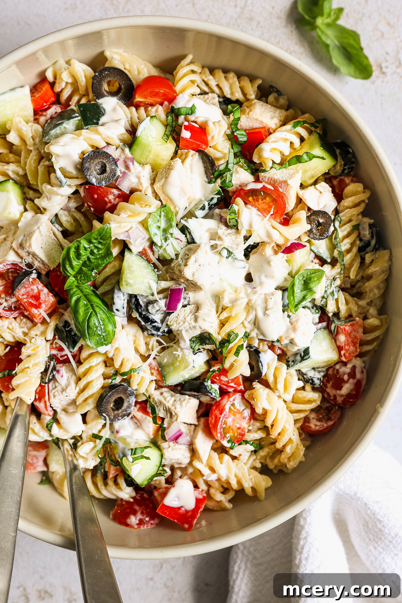 Flavorful Chicken Pasta Salad 2 chicken pasta salad in a white bowl garnished wiht basil.