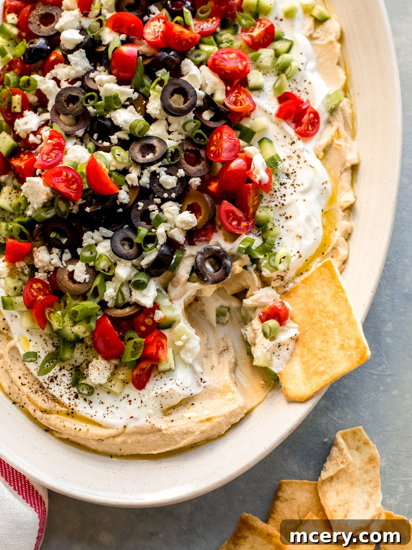 Stacked Hummus Delight 3 Close-up view of a generously loaded hummus dip with vibrant toppings