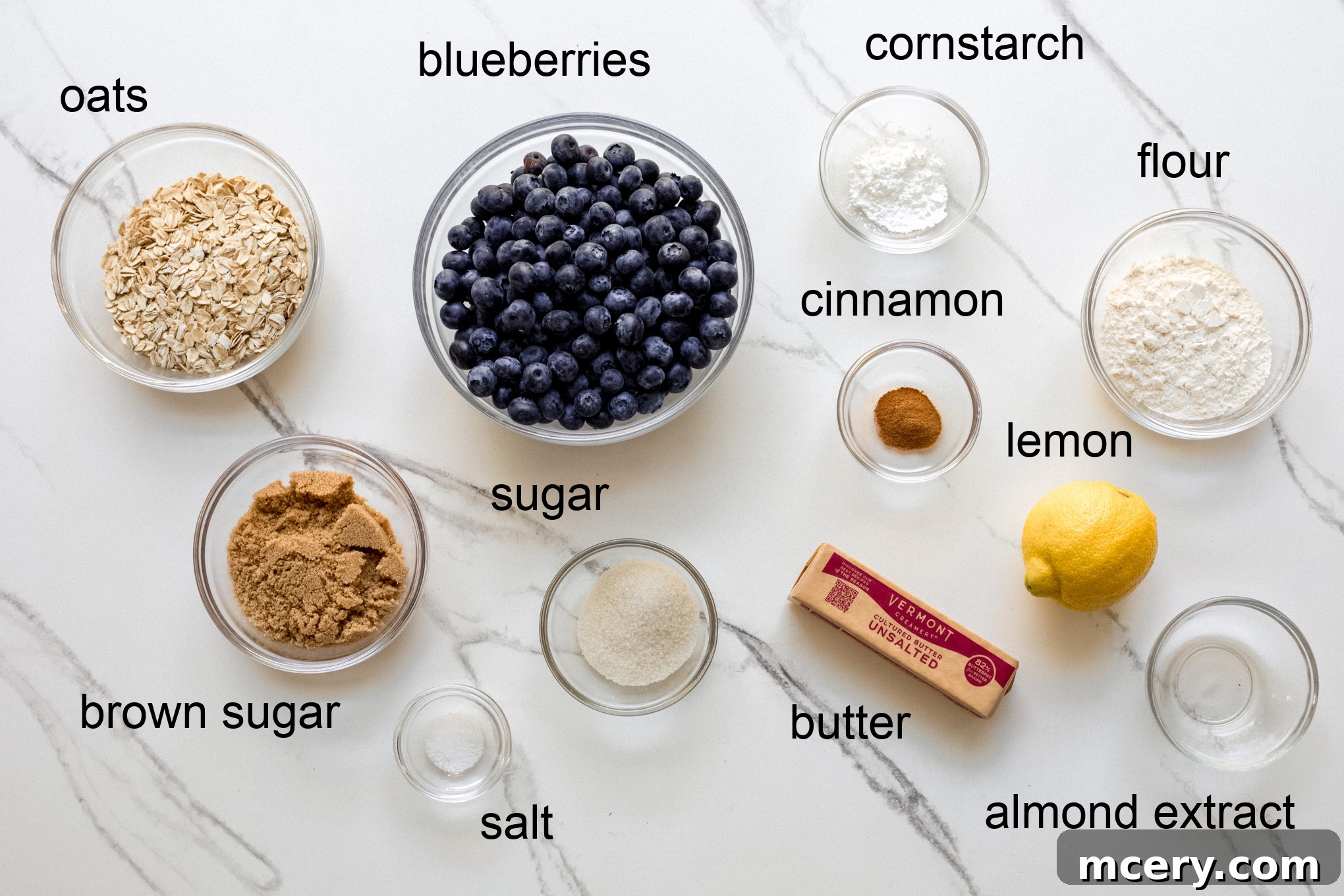 Golden Oat Topped Blueberry Crisp 3 Ingredients for blueberry crisp laid out on a table, including fresh blueberries, oats, flour, sugar, and lemon.