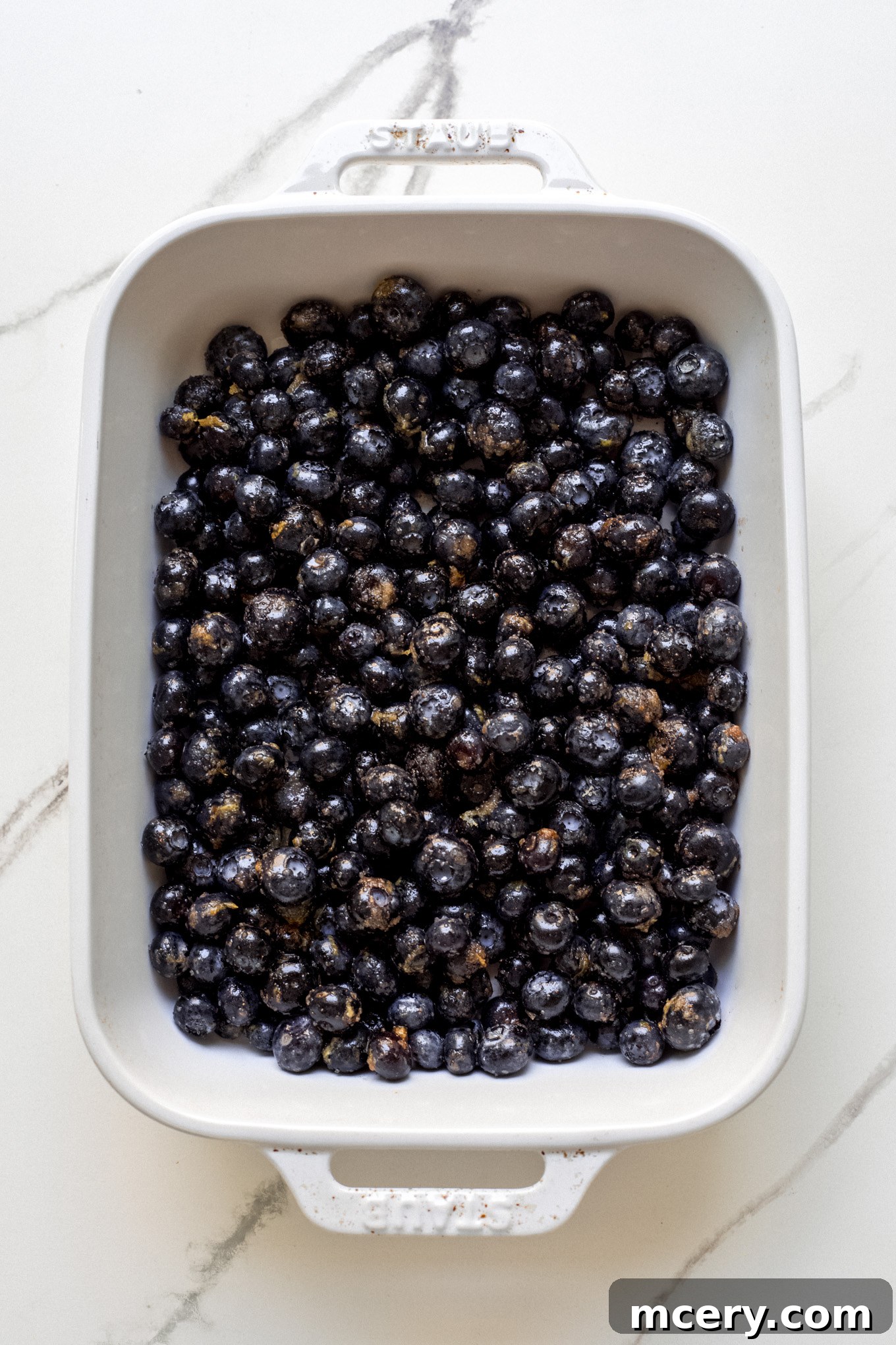 Golden Oat Topped Blueberry Crisp 5 Fresh blueberries spread evenly inside a white baking dish.