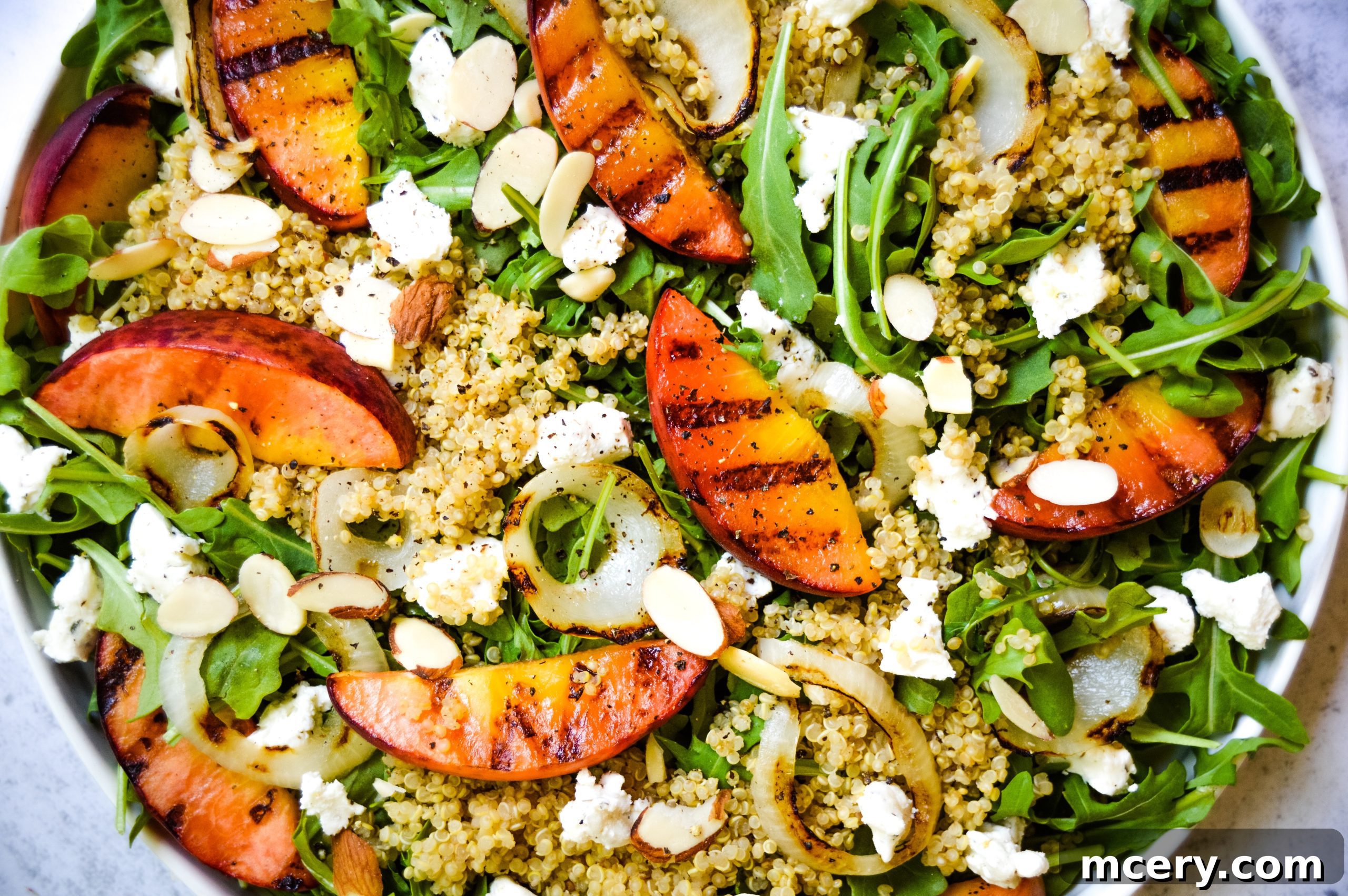 Smoky Grilled Peach and Aromatic Goat Cheese Salad 3 Close-up of the grilled peach and herbed goat cheese salad, showing the creamy goat cheese and colorful ingredients perfectly blended on a white plate.