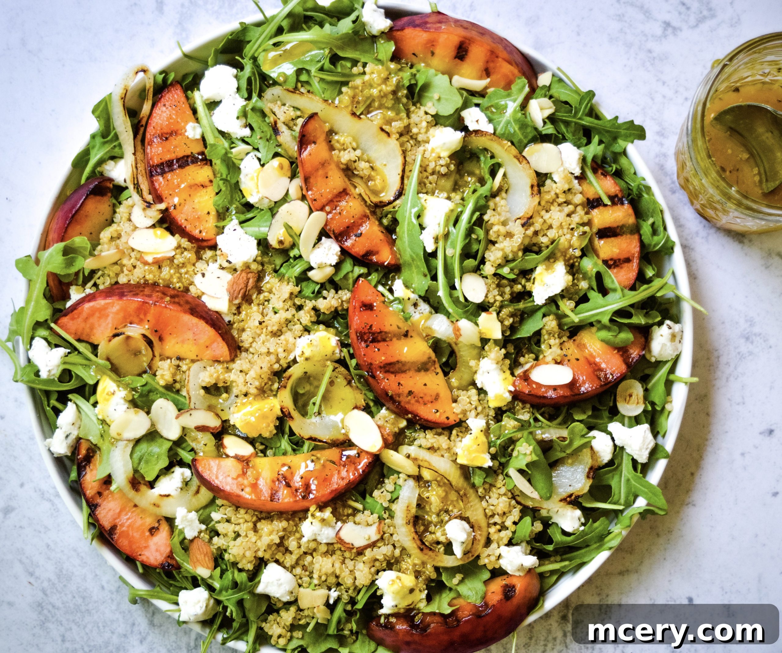 Smoky Grilled Peach and Aromatic Goat Cheese Salad 4 A beautifully composed grilled peach salad on a white plate, garnished and ready to be served, highlighting its freshness and appeal.