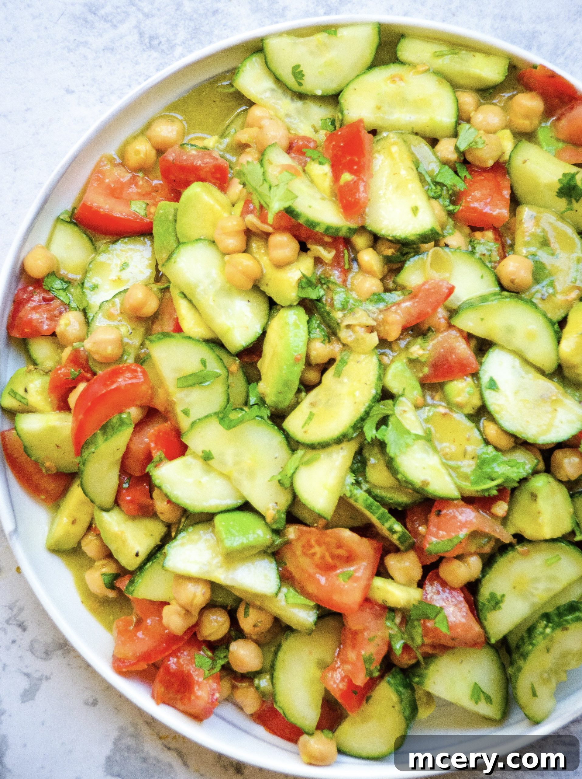 Refreshing Cucumber Avocado Salad with Tomatoes and Chickpeas 2 A beautifully arranged Healthy Cucumber Salad with Tomatoes, Avocado & Chickpeas in a glass bowl, showcasing fresh ingredients and vibrant colors.