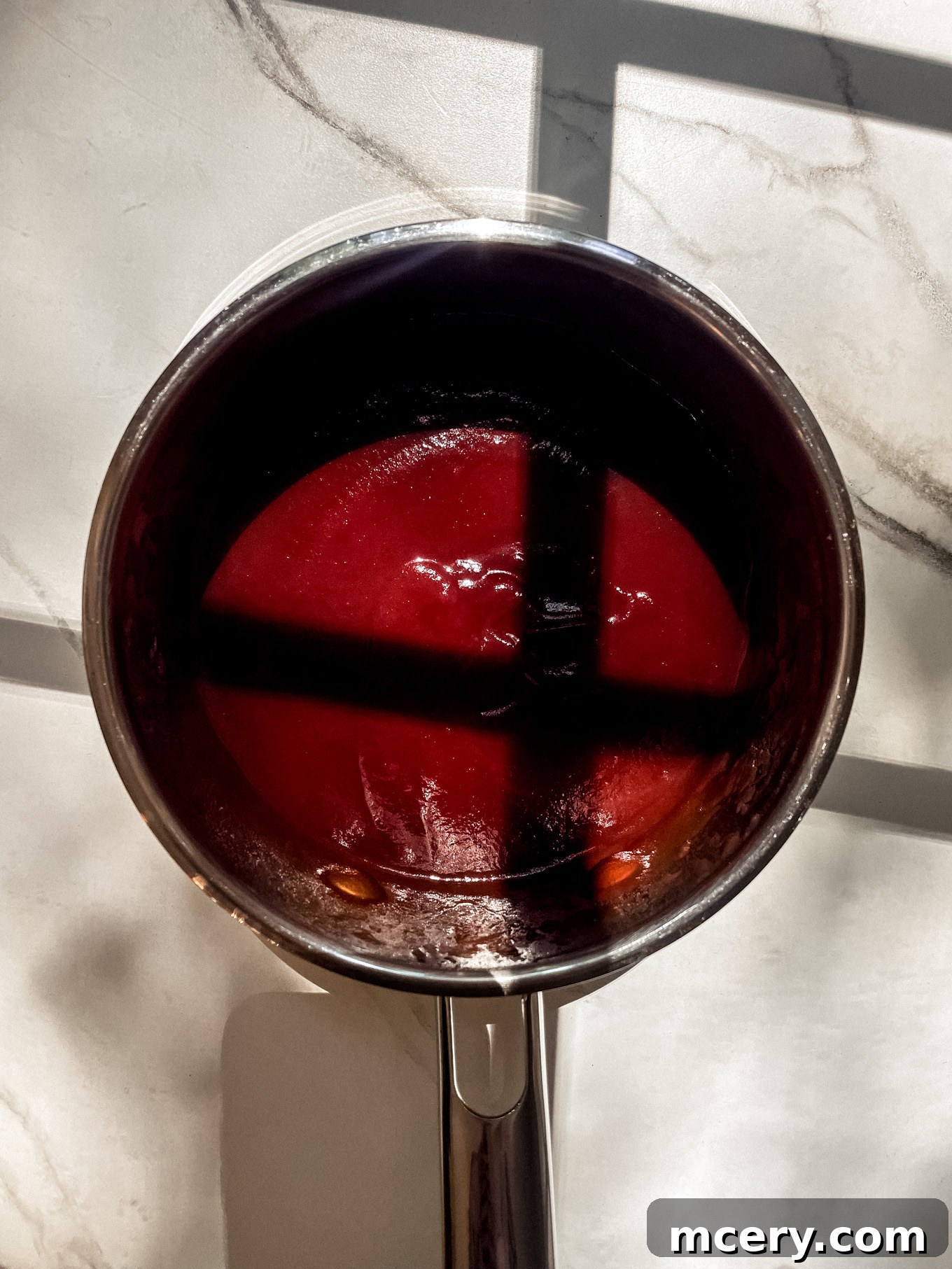 Three Ingredient BBQ Magic 5 Homemade BBQ sauce gently simmering in a saucepan on the stovetop, with steam gently rising, indicating it's cooking perfectly.