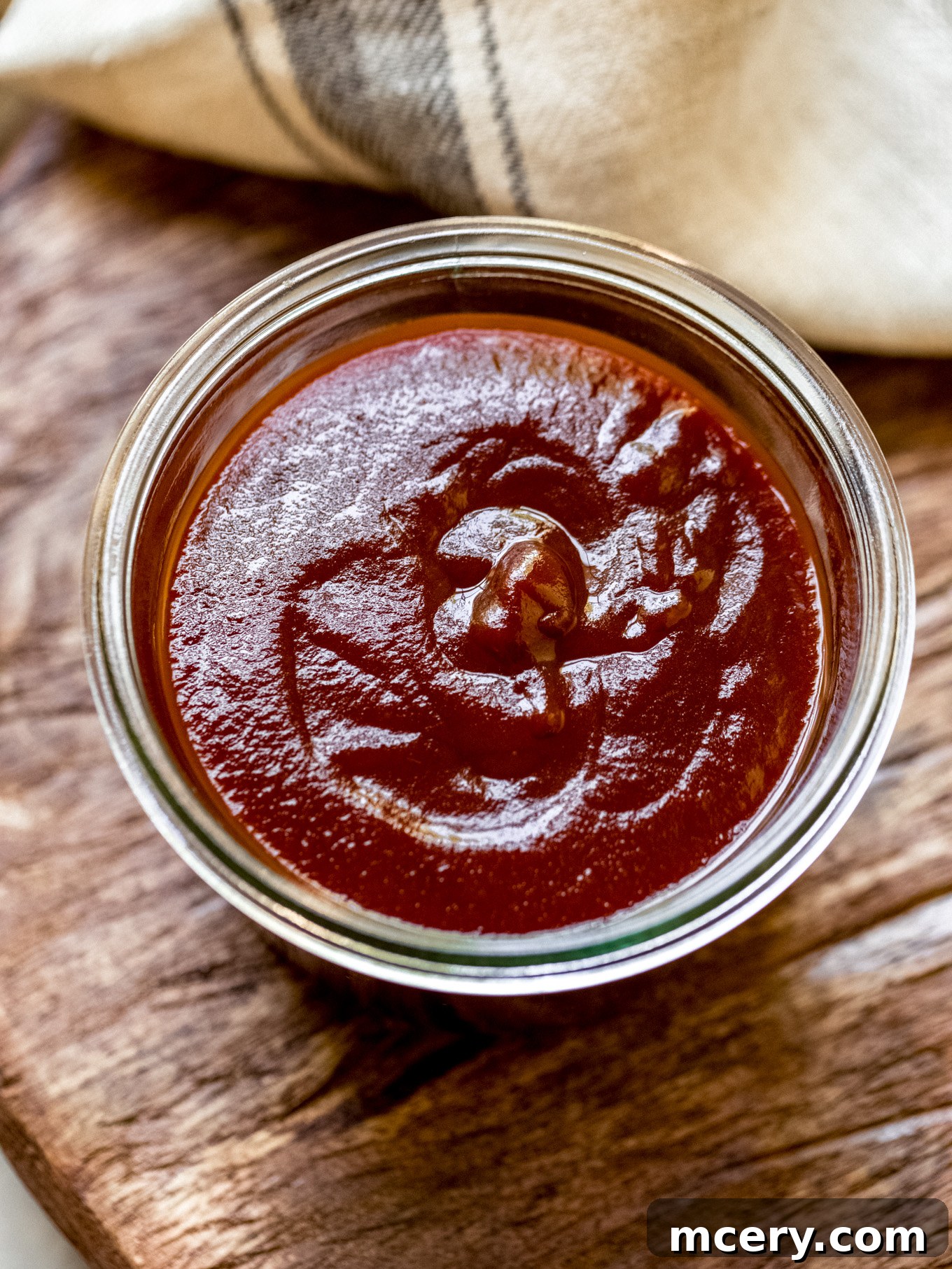 Three Ingredient BBQ Magic 6 A transparent glass container filled with rich, homemade 3-ingredient BBQ sauce, resting on a wooden table, ready for airtight storage.