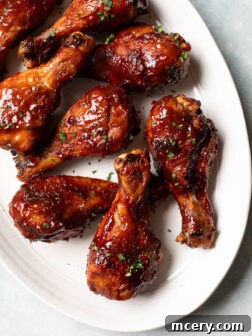 Close up of perfectly roasted bbq chicken legs on a platter, garnished with fresh herbs.