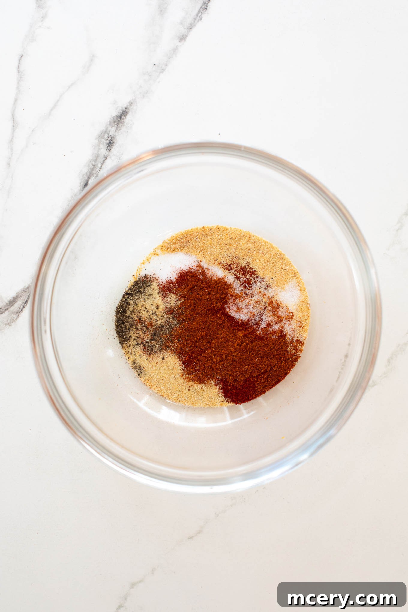 Sweet & Smoky Oven-Baked BBQ Drumsticks 5 A small glass bowl filled with a vibrant orange spice mixture.