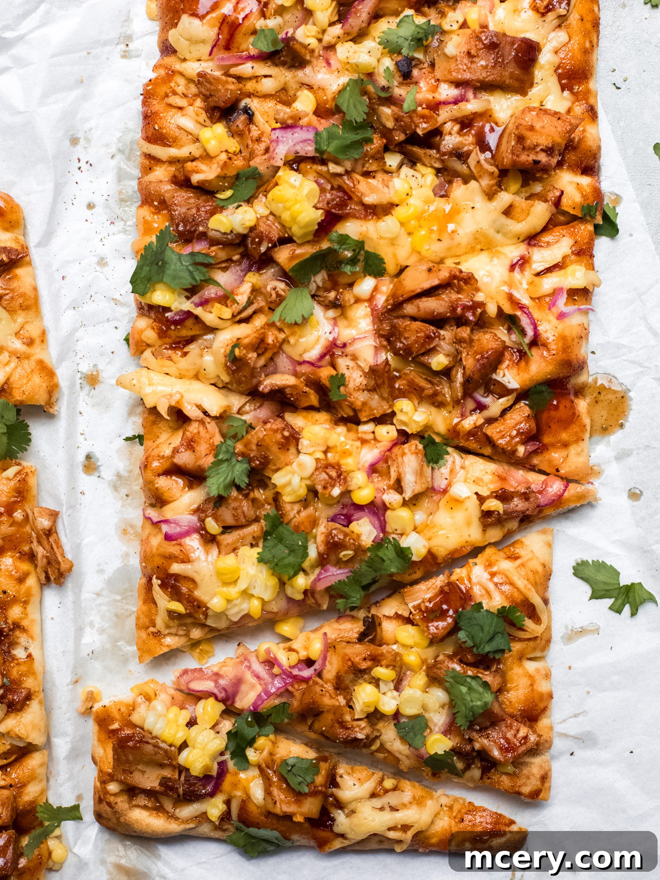 Smoky BBQ Chicken Flatbread 2 Delicious BBQ chicken flatbread on white parchment paper, ready to be served.