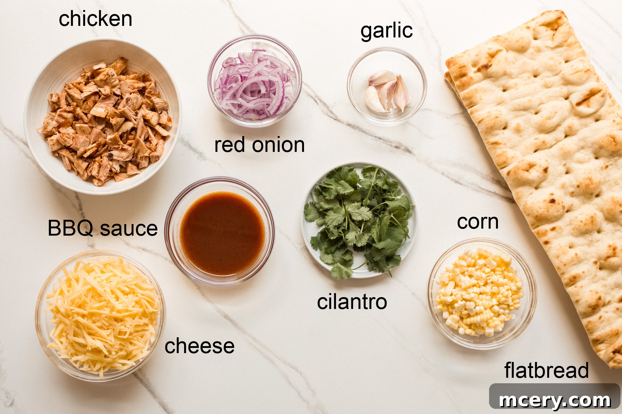 Smoky BBQ Chicken Flatbread 3 A selection of fresh ingredients laid out for making barbecue flatbread, including chicken, corn, onion, cheese, and sauce.