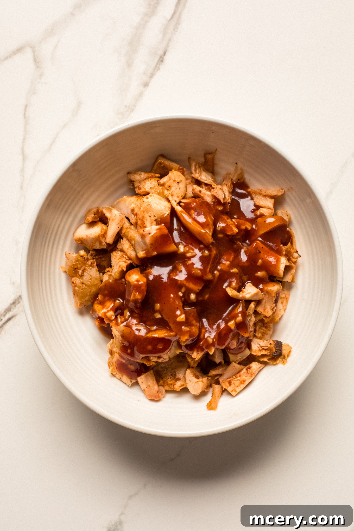 Smoky BBQ Chicken Flatbread 5 Diced cooked chicken being tossed with a portion of the BBQ sauce mixture.