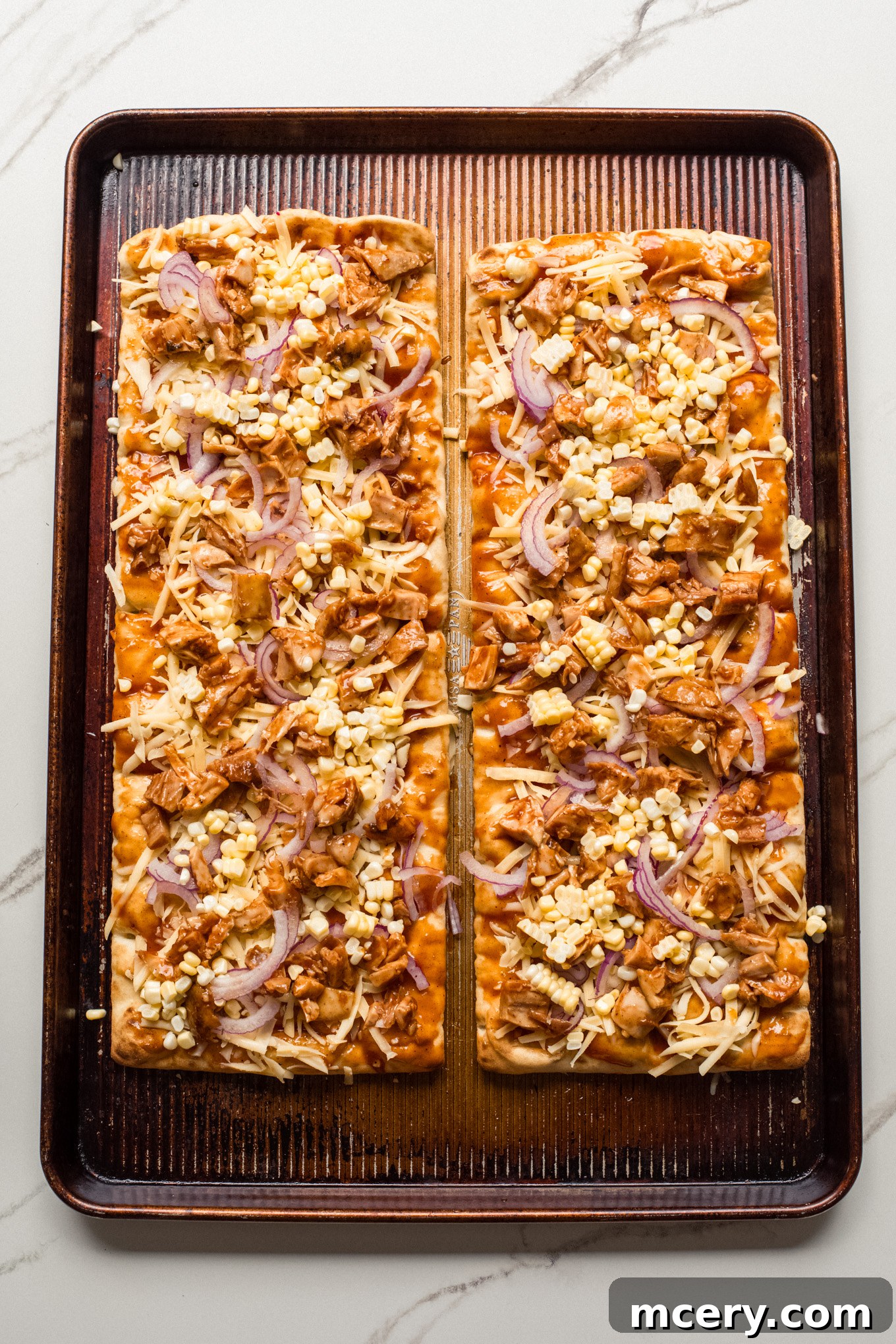 Smoky BBQ Chicken Flatbread 7 Flatbread topped with chicken, corn, onions, and shredded cheese, ready for baking.