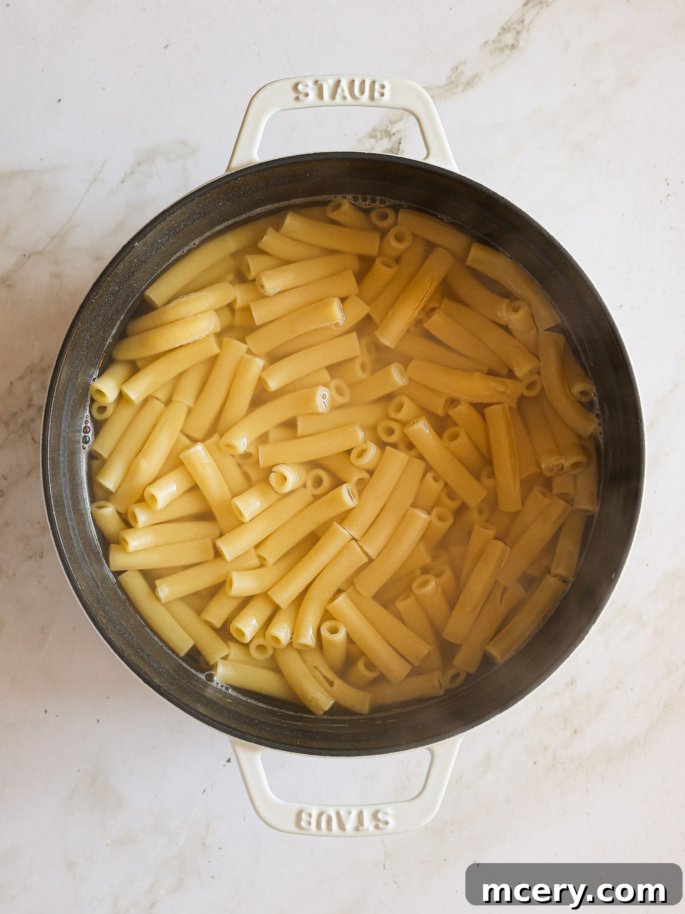 Golden Baked Ziti Delight 4 Cooked ziti pasta, perfectly al dente, draining in a pot.