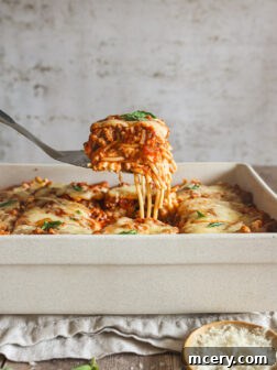 Baked spaghetti in a white casserole dish, showing off its golden crust and bubbly cheese.