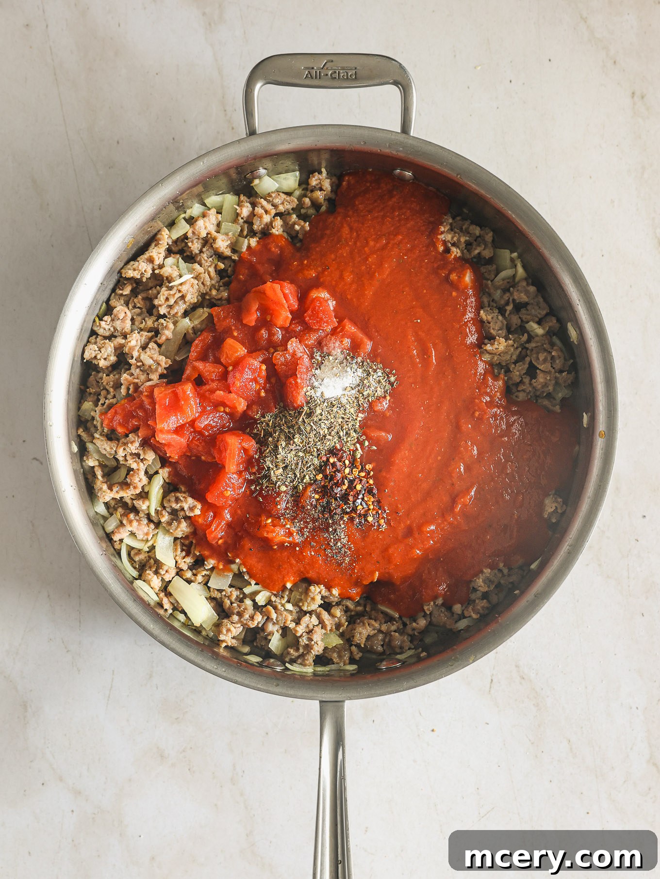 Effortless Creamy Ricotta Spaghetti Bake 6 A rich, red meat sauce simmering in a skillet, filled with ground sausage, diced tomatoes, and marinara.
