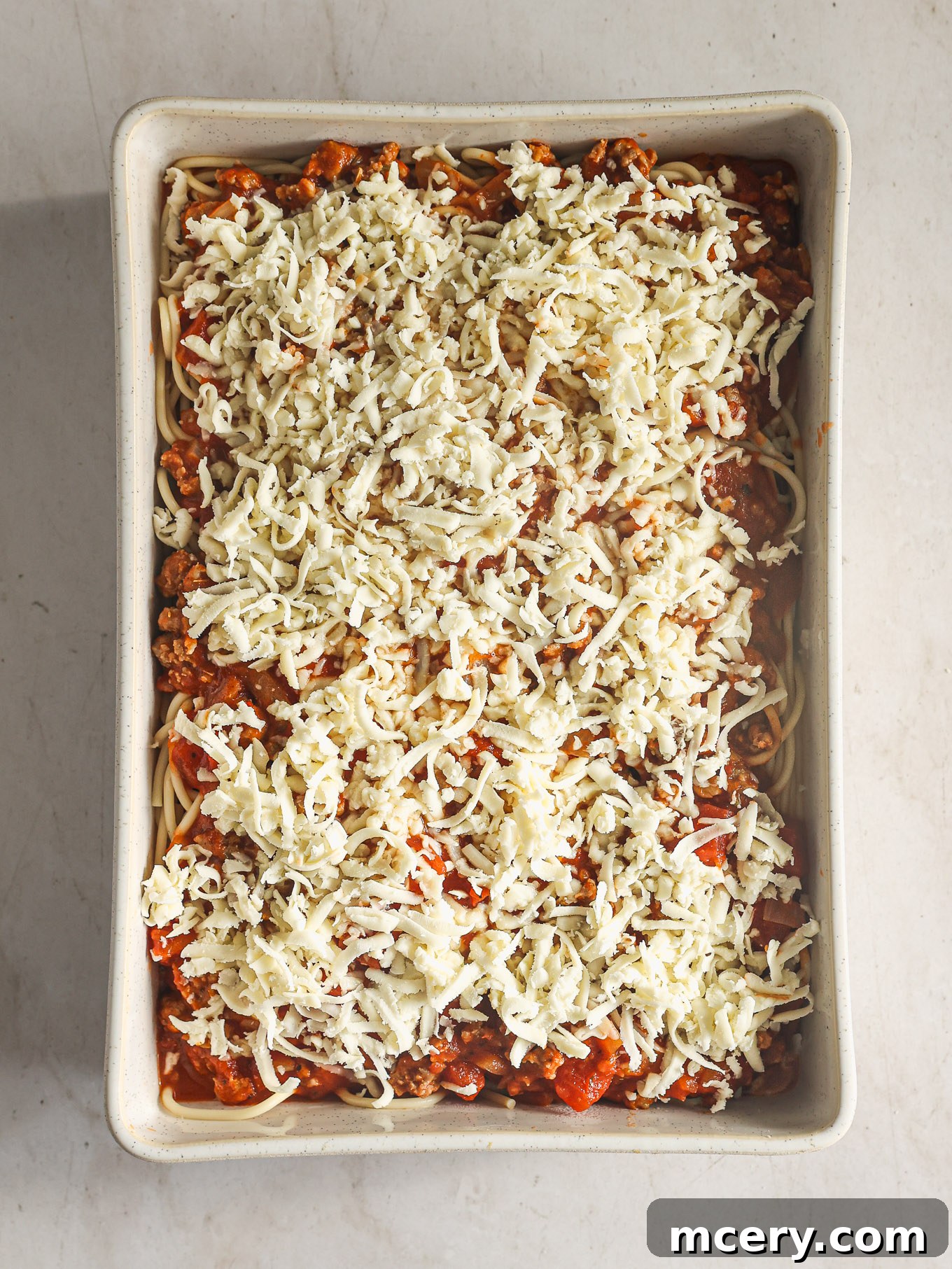 Effortless Creamy Ricotta Spaghetti Bake 9 The completed spaghetti casserole in a baking dish, generously topped with the remaining shredded mozzarella cheese, ready for baking.