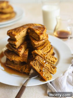 Stacked and cut pumpkin spice pancakes on a plate, ready to be enjoyed.