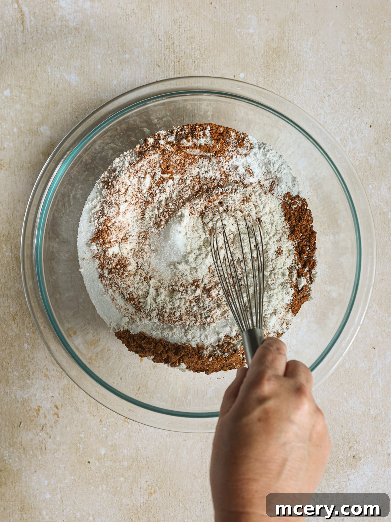 Whip Up Fluffy Pumpkin Pancakes 4 Dry ingredients like flour, sugar, and spices are neatly measured and combined in a large glass mixing bowl.