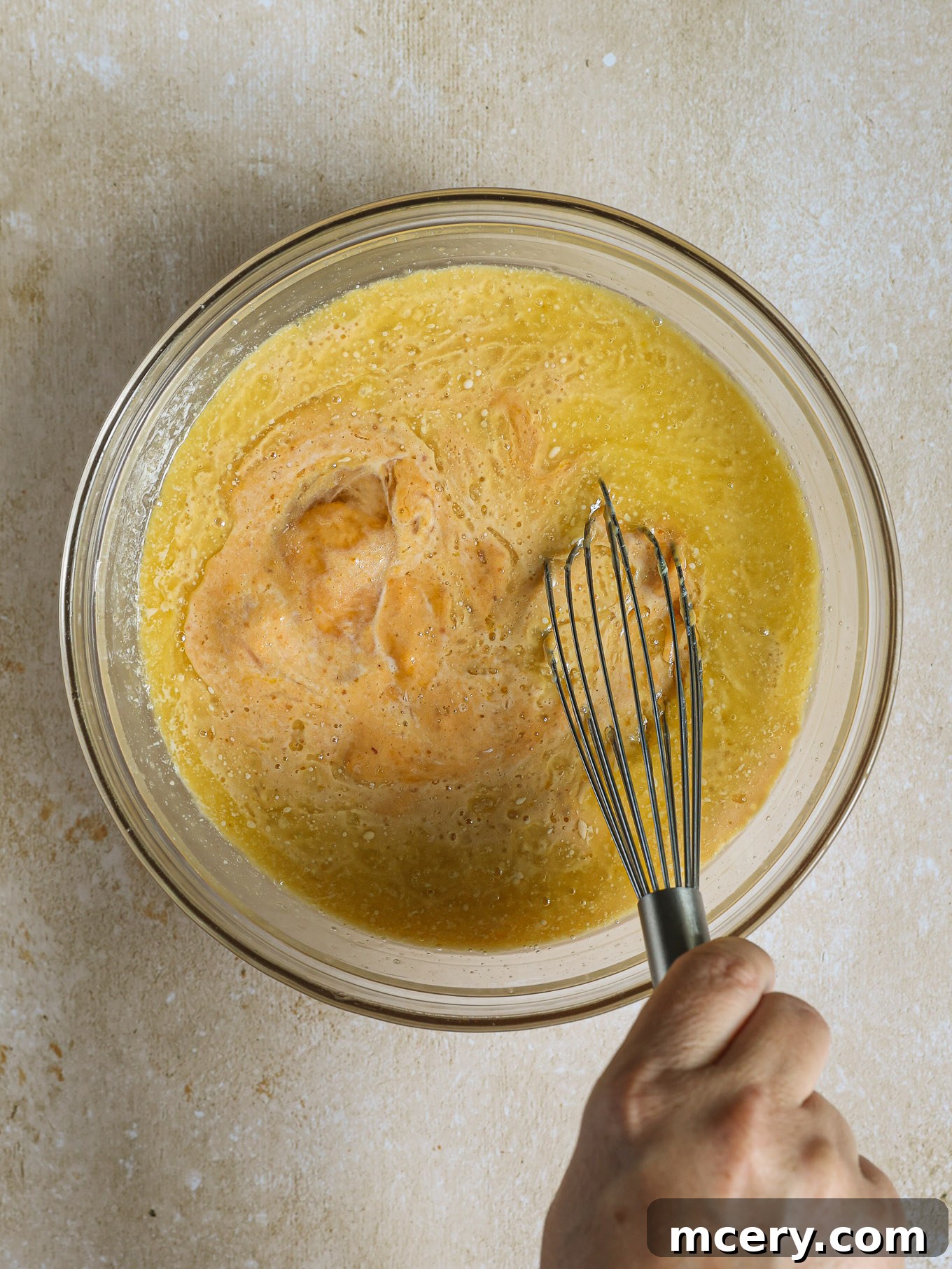Whip Up Fluffy Pumpkin Pancakes 5 Wet ingredients including pumpkin puree, milk, melted butter, vanilla, and an egg are whisked together in a separate glass bowl until smooth.