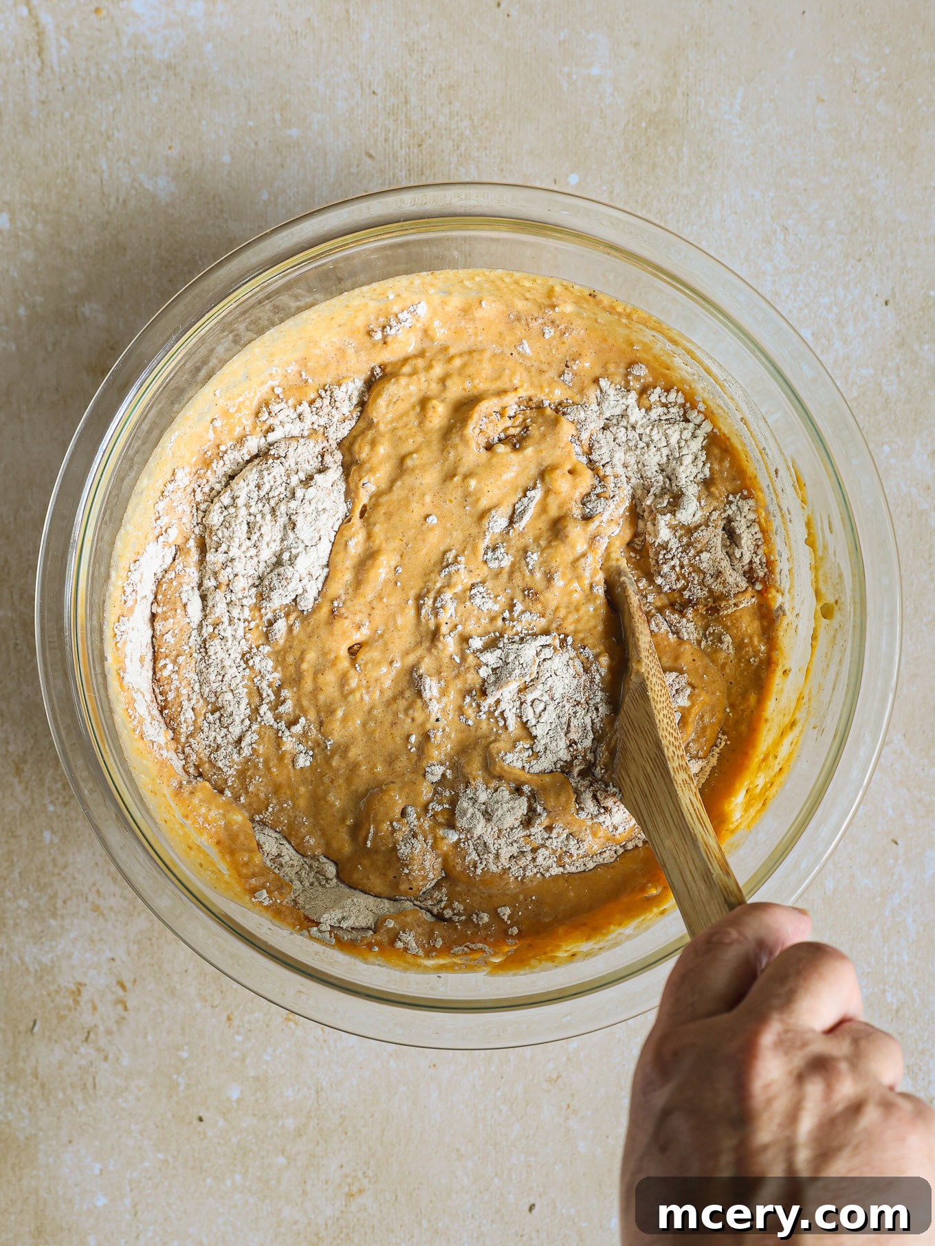 Whip Up Fluffy Pumpkin Pancakes 6 Pumpkin pancake batter, thick and creamy with a few small lumps, rests in a glass mixing bowl.