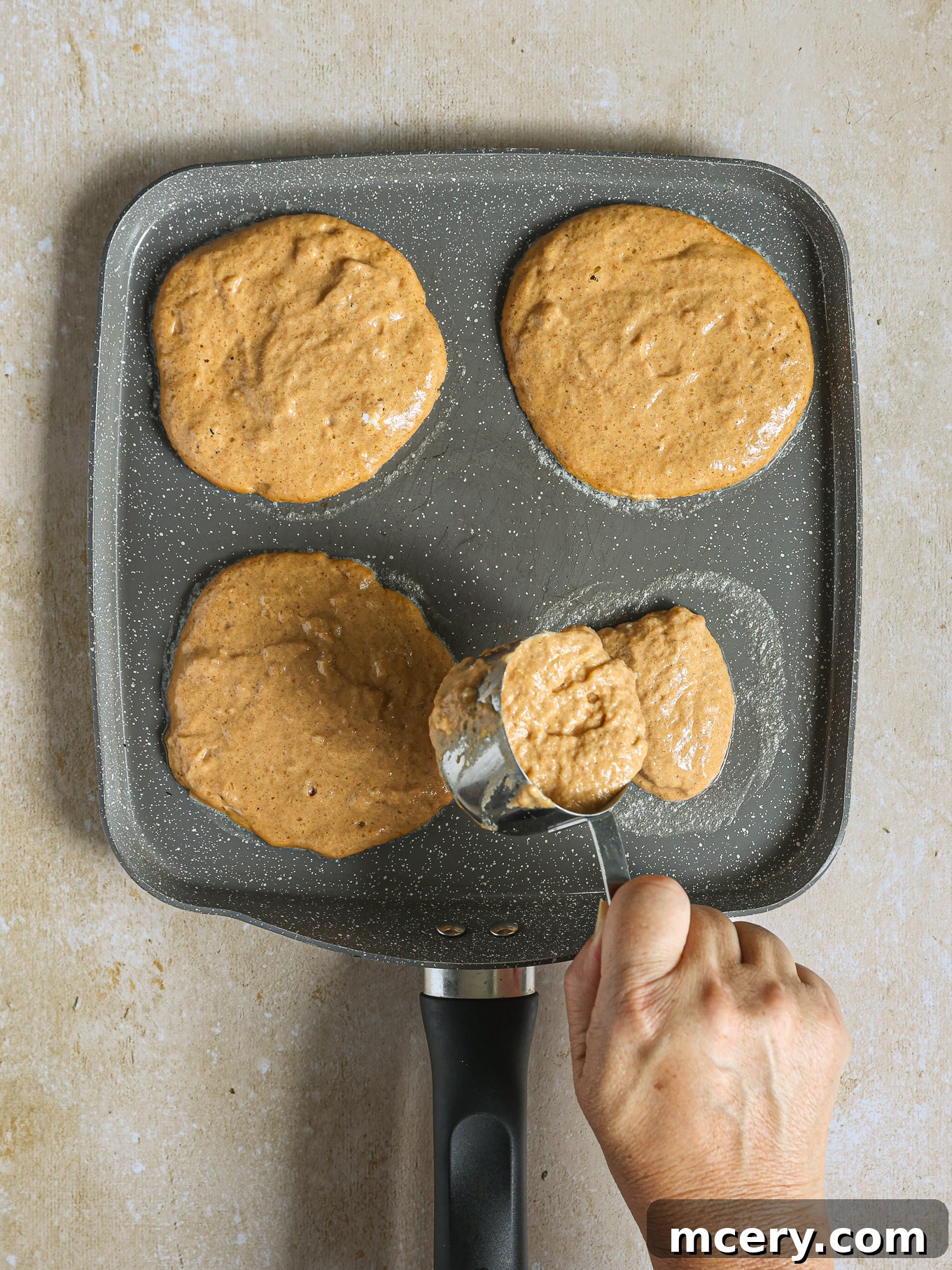 Whip Up Fluffy Pumpkin Pancakes 7 Several pumpkin pancakes cooking on a hot griddle, showing bubbles forming on the surface.