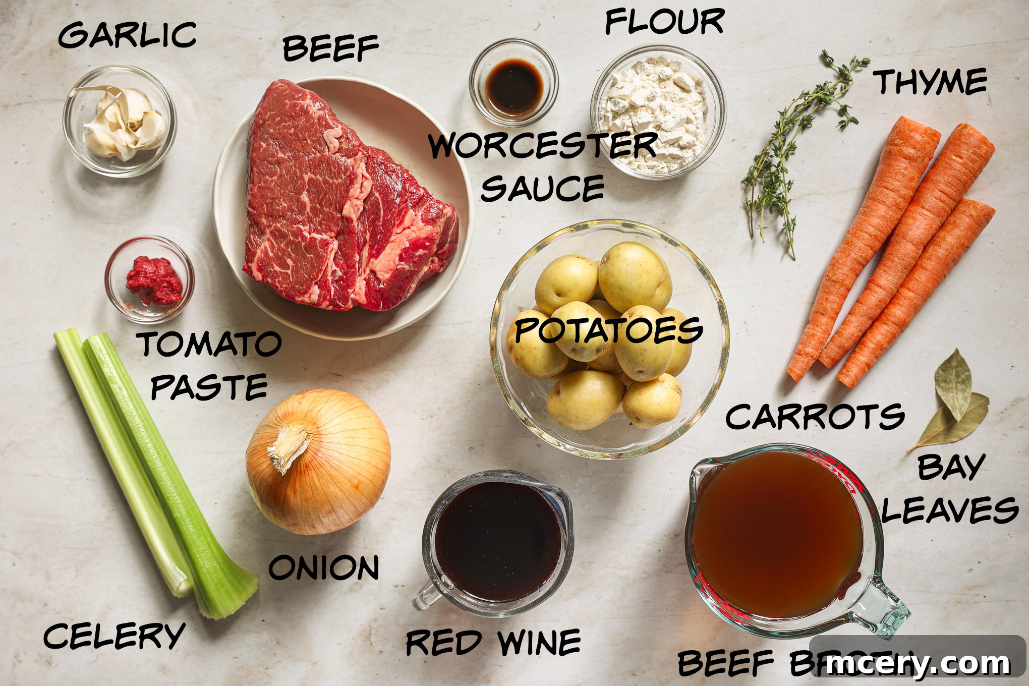 Carefully arranged ingredients for beef stew, showcasing fresh chuck roast, vibrant vegetables, and essential seasonings on a rustic wooden surface.