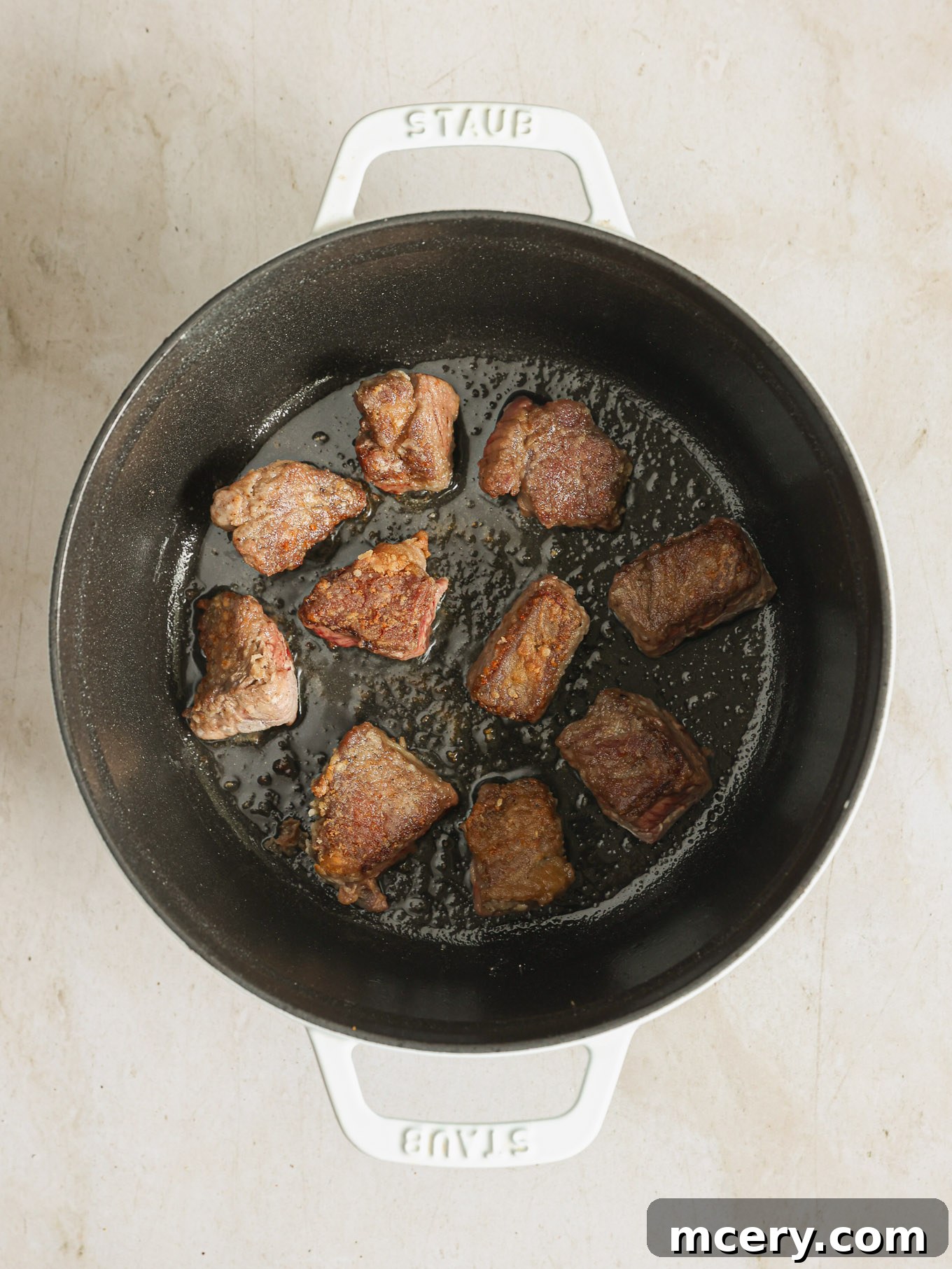 Expertly seared beef cubes with a rich, deep brown crust, resting beautifully in a hot Dutch oven.