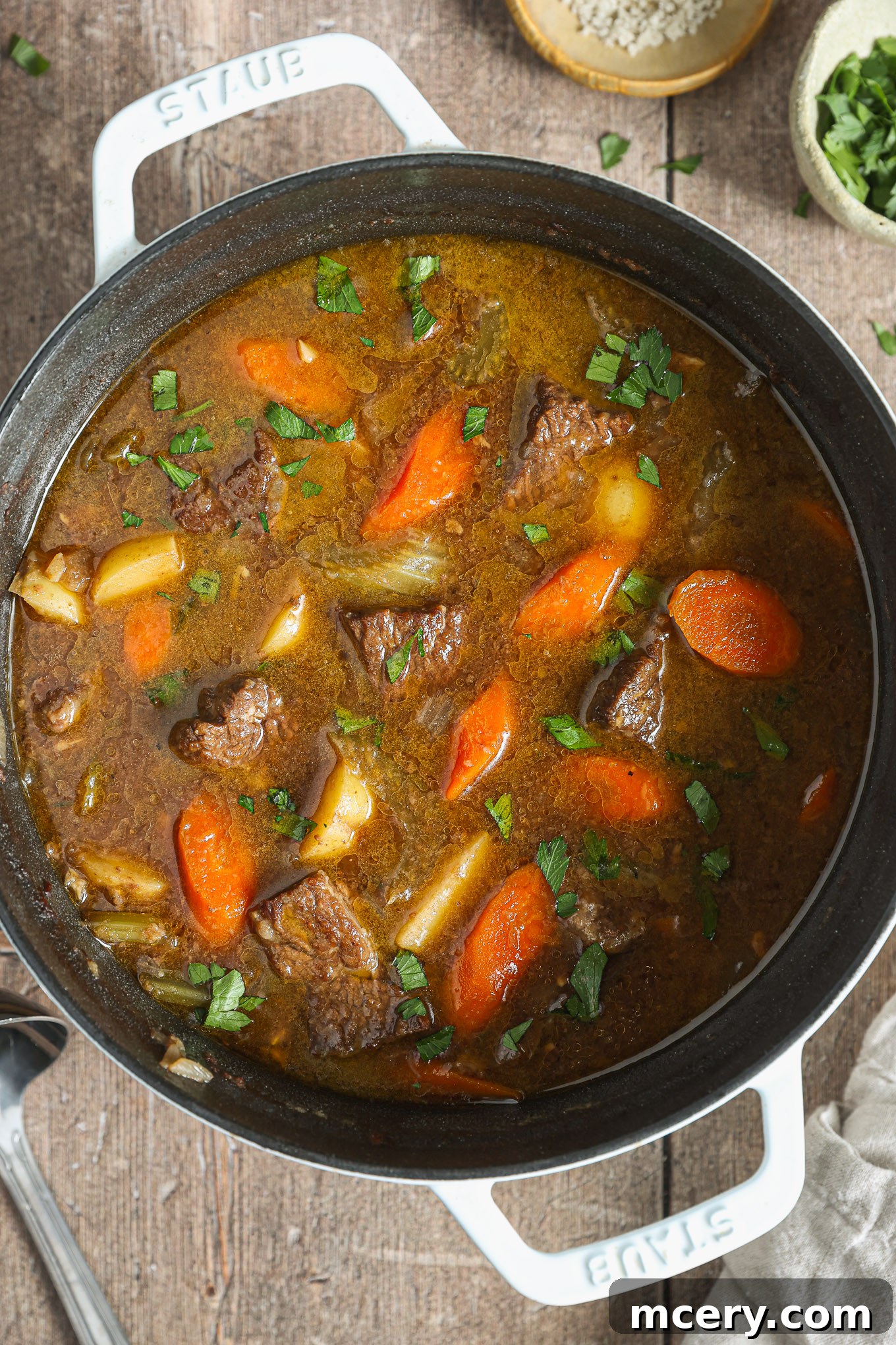 A close-up view of the rich, savory beef stew simmering gently in a rustic Dutch oven, indicating it's almost ready to be served and enjoyed.