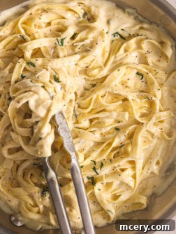 Fettuccine pasta generously coated in homemade Alfredo sauce, served in a pan.