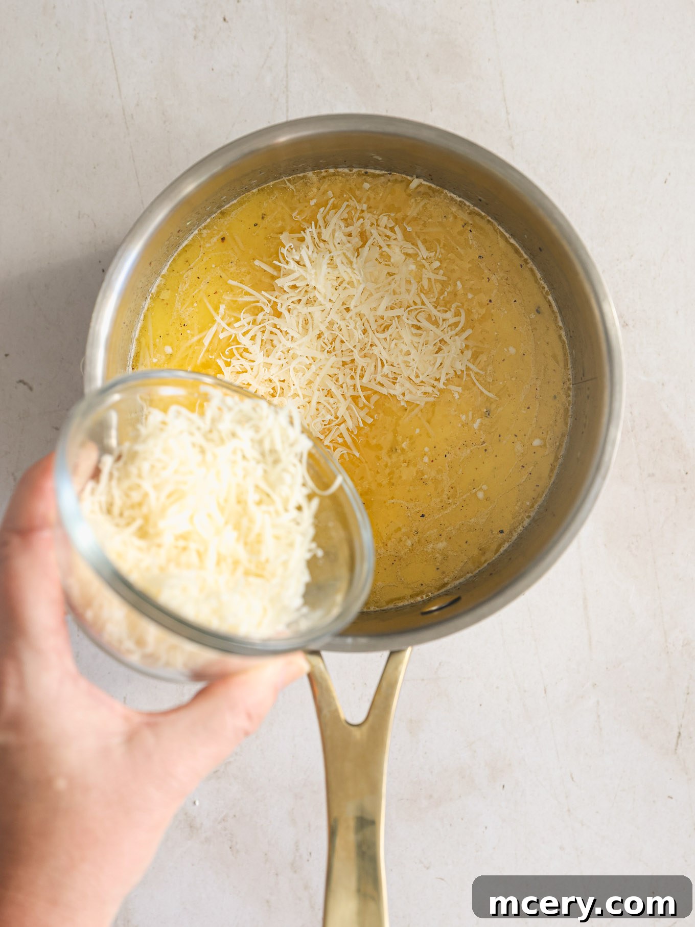 Homemade Alfredo Perfection 6 Freshly grated Parmesan cheese being sprinkled evenly over the simmering cream mixture in the saucepan.