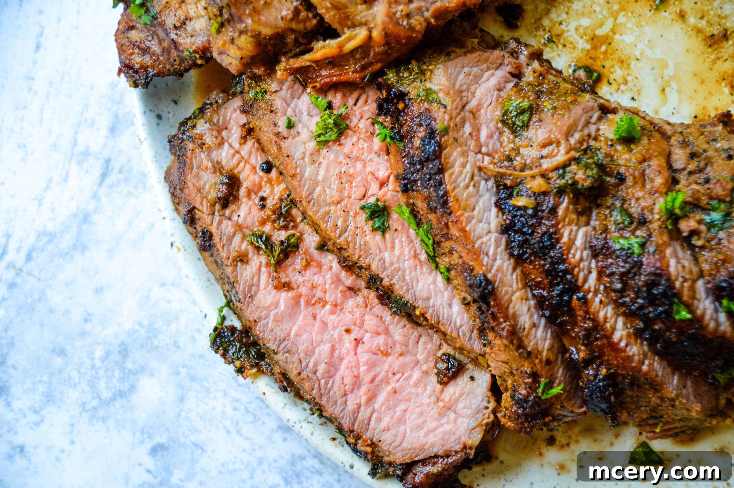A stunning full view of a perfectly oven-roasted Tri-Tip, beautifully sliced and arranged on a platter with fresh herbs, ready for serving.