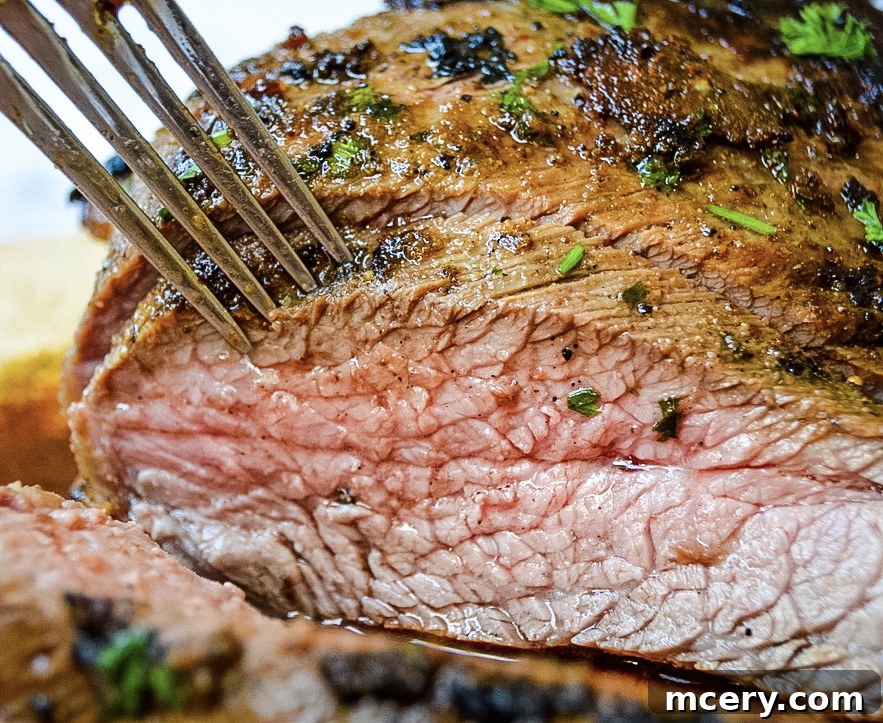 A bowl filled with a fresh, aromatic spice rub, featuring finely chopped parsley and various herbs and spices.