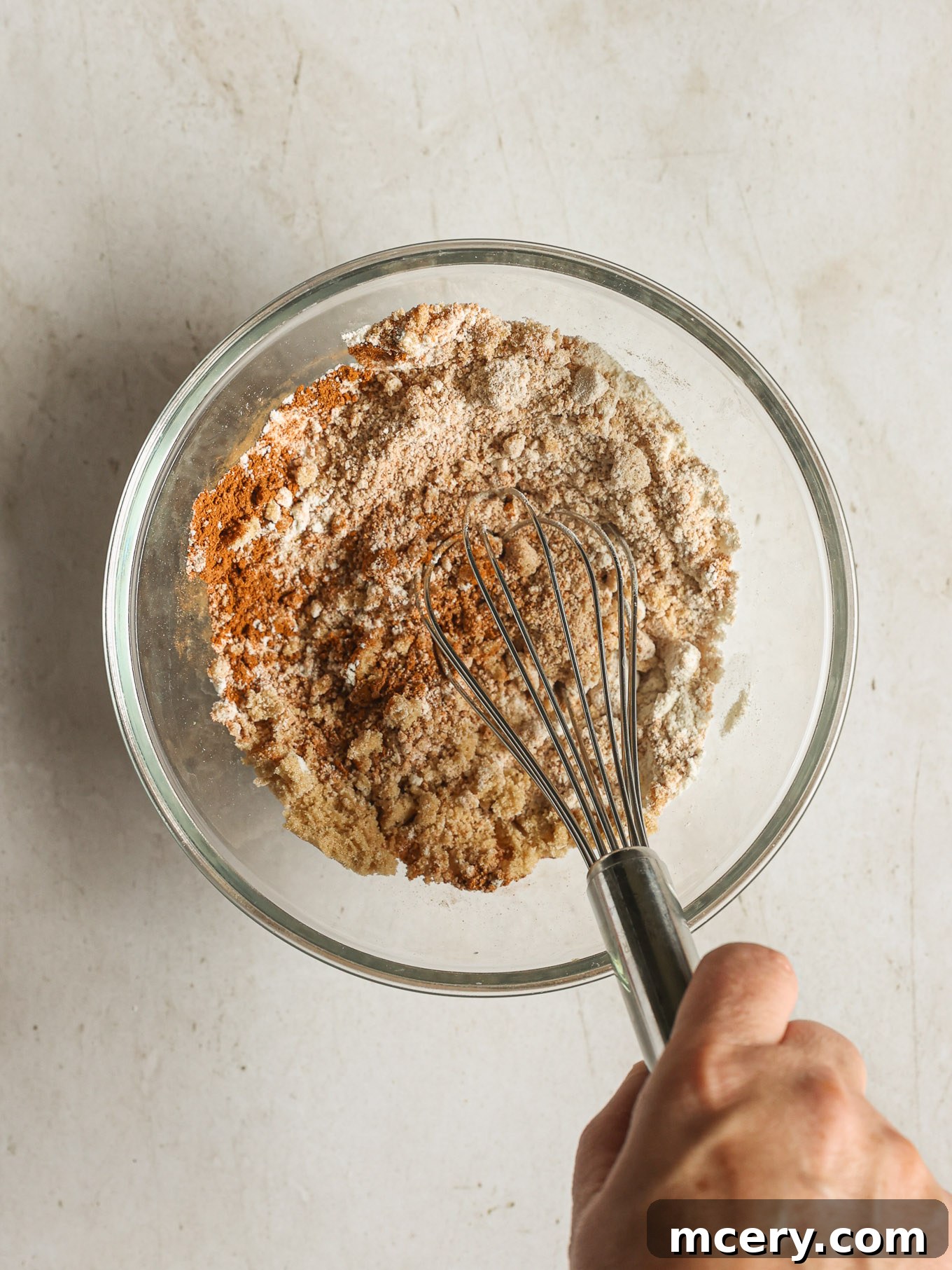 Cozy Pumpkin Crumble Coffee Cake 4 Dry ingredients for the streusel topping, including flour, brown sugar, cinnamon, and salt, are whisked together in a clear glass bowl.