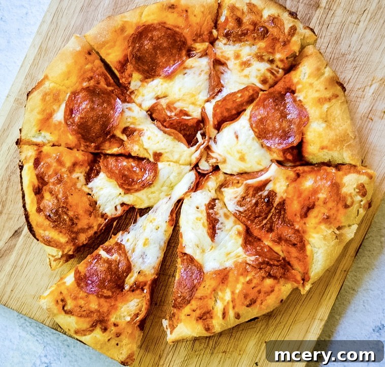 Fast and Easy Food Processor Pizza Dough 10 A delicious, fully topped homemade pizza, freshly out of the oven, sliced and ready to be served on a wooden board.