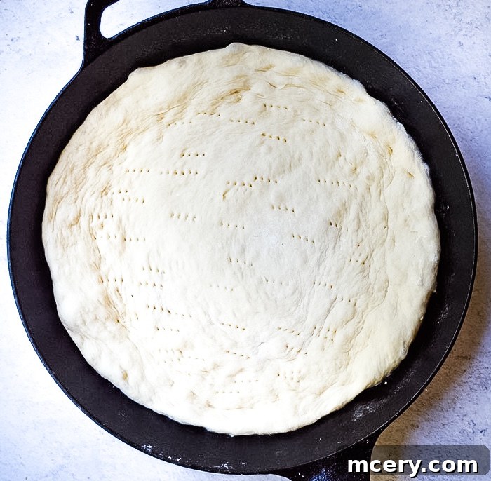 Fast and Easy Food Processor Pizza Dough 7 Pizza dough disc with fork pricks across the surface and a layer of red sauce applied, ready for cheese and toppings.