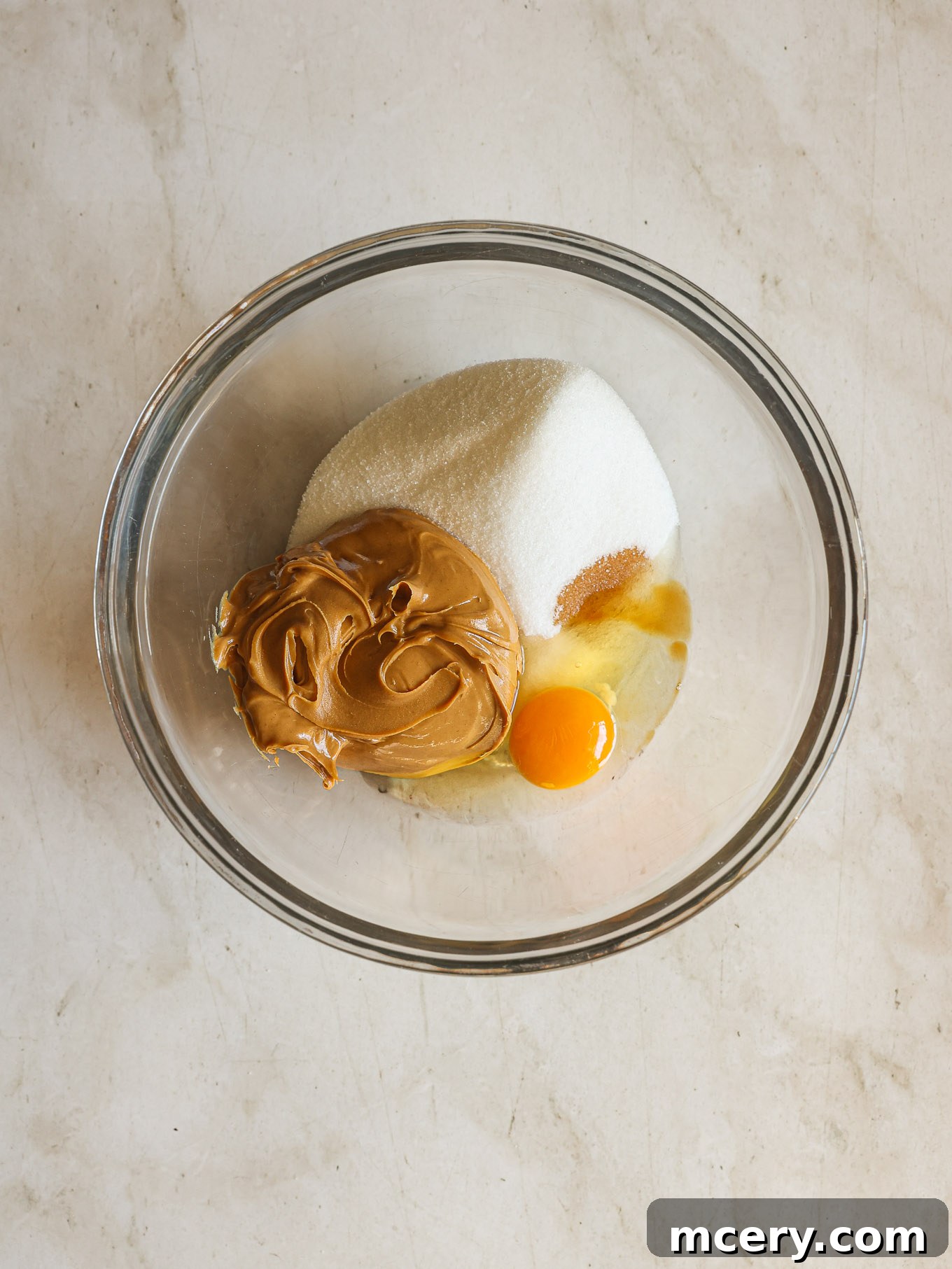 Effortless 4-Ingredient Peanut Butter Cookies 4 All four ingredients – sugar, peanut butter, egg, and vanilla – combined in a mixing bowl, ready to be stirred.