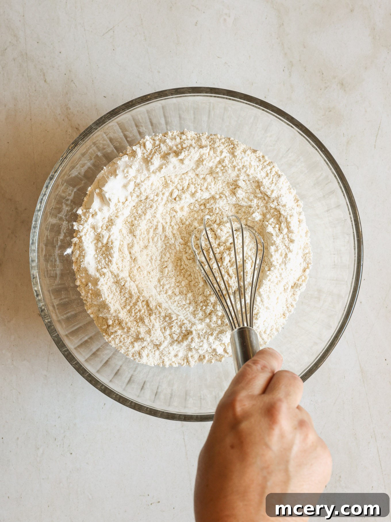 No-Bake Crispy Cornflake Treats 4 Dry ingredients for cornflake cookies, including flour, baking soda, and salt, mixed in a clear glass bowl.