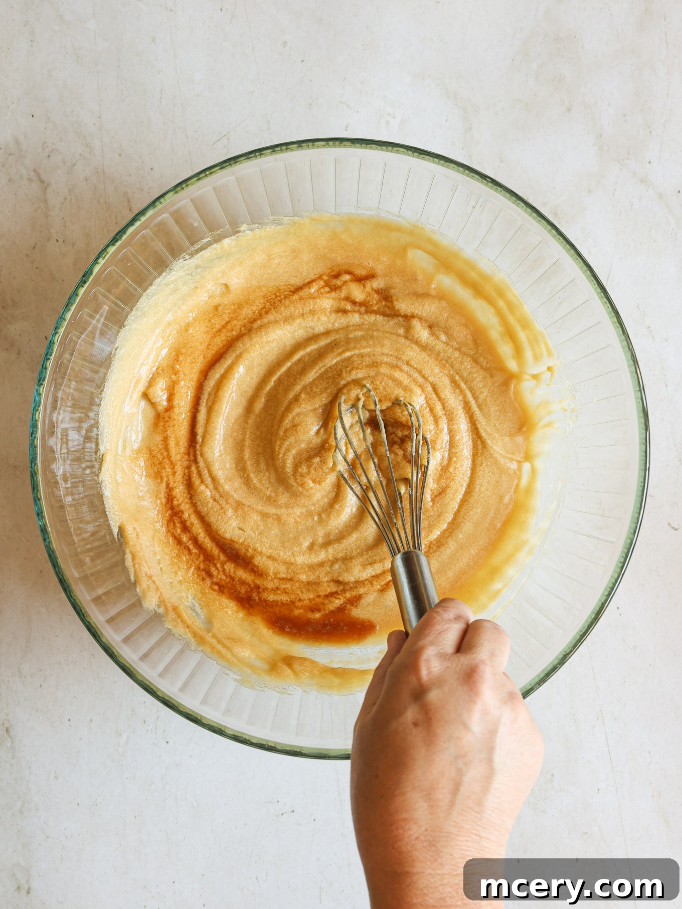 No-Bake Crispy Cornflake Treats 6 Wet and dry ingredients for cornflake cookies partially mixed together in a glass bowl, showing the beginning of dough formation.