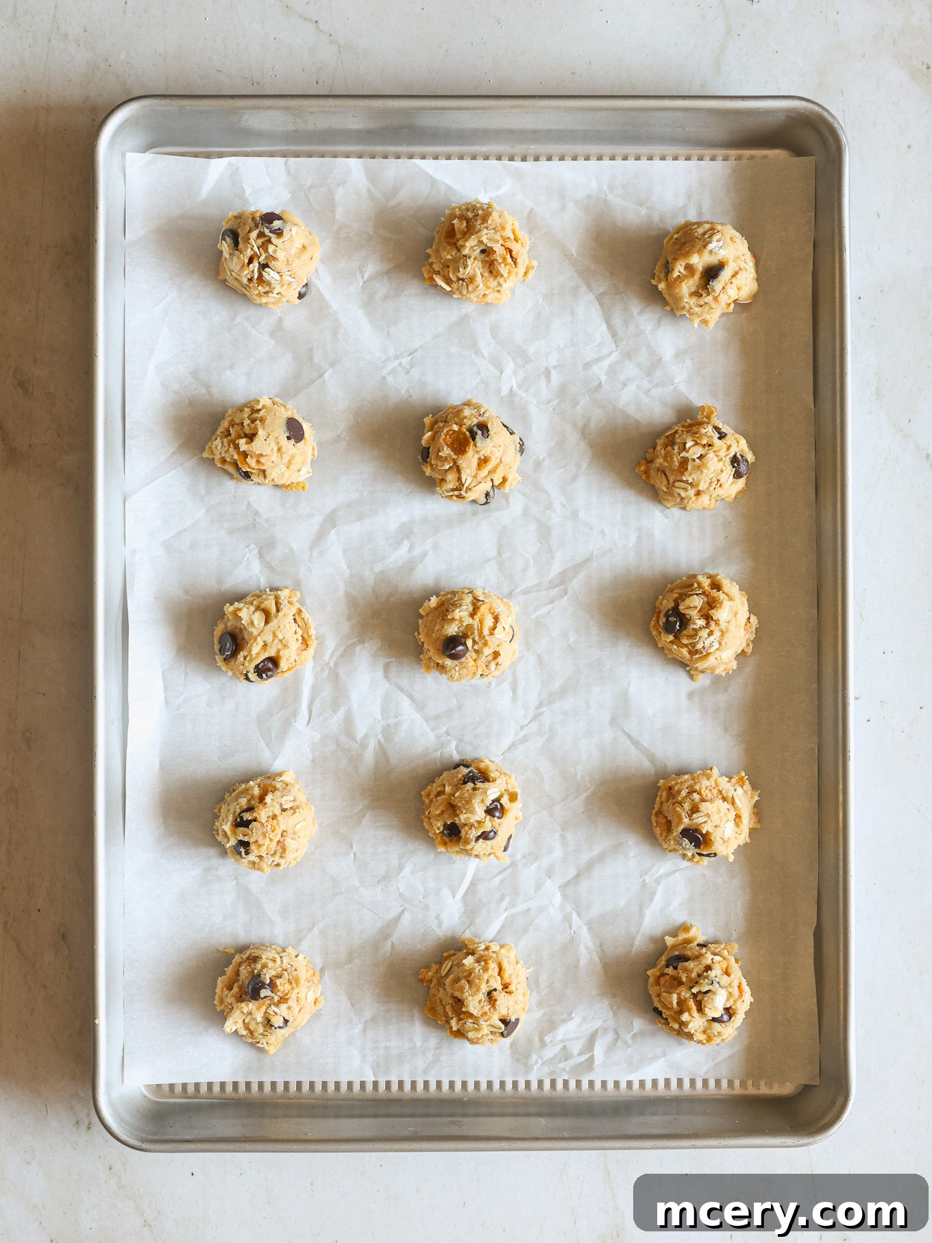 No-Bake Crispy Cornflake Treats 9 Raw cookie dough balls portioned and placed on a baking sheet lined with parchment paper, ready for baking.