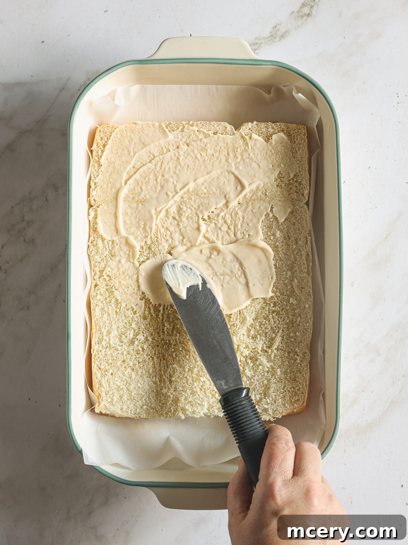 mayonnaise spread on the bottom half of sliced hawaiian rolls.