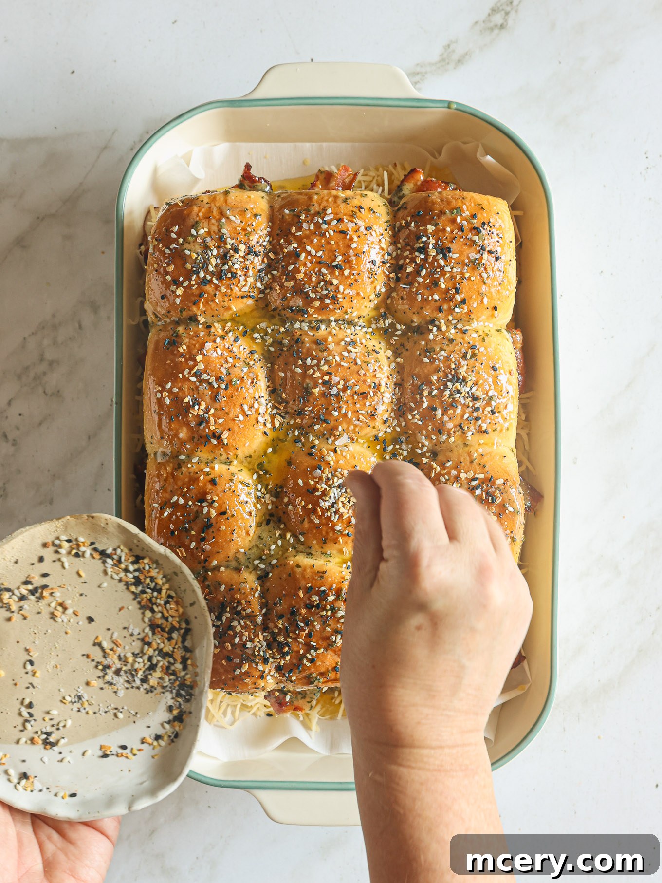 top of hawaiian rolls sprinkled with bagel seasoning.