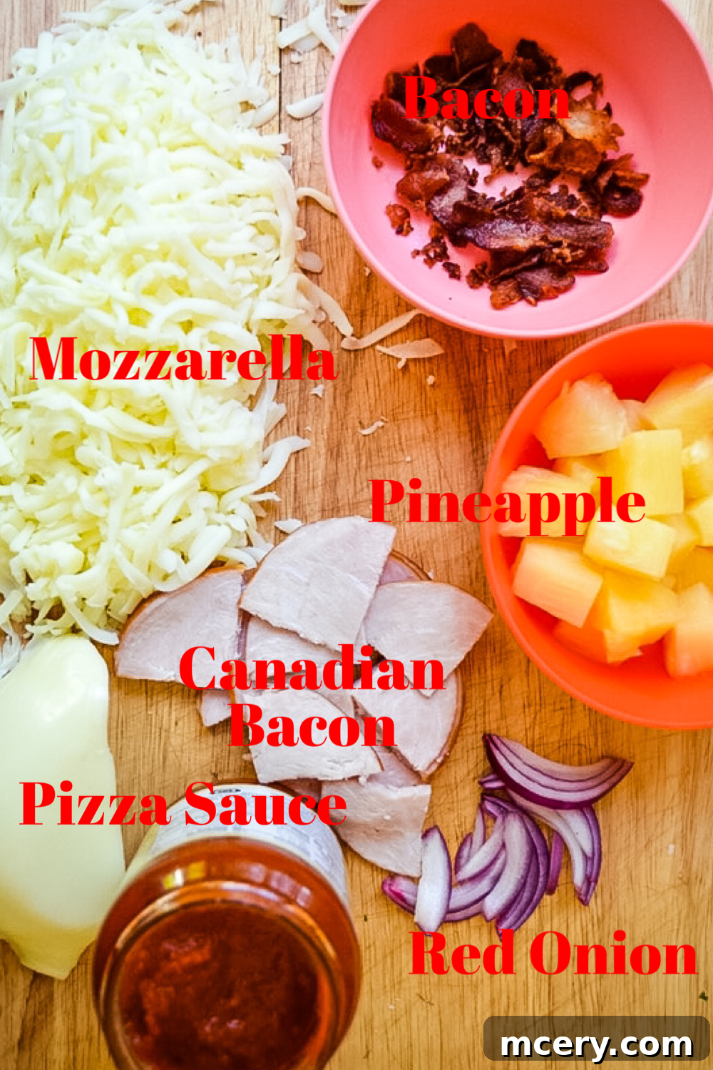 An appealing overhead shot showcasing all the fresh, prepped ingredients for a Hawaiian pizza laid out on a wooden board: pizza sauce, shredded mozzarella cheese, juicy pineapple chunks, diced ham, sliced red onion, and crispy bacon crumbles.