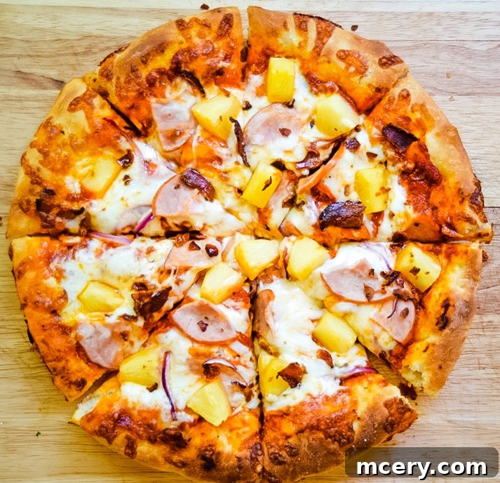 Close-up of a sliced Hawaiian Pizza on a wooden surface, topped with ham, pineapple, and melted cheese. The pizza crust is golden brown, and the toppings are evenly distributed across the slices.