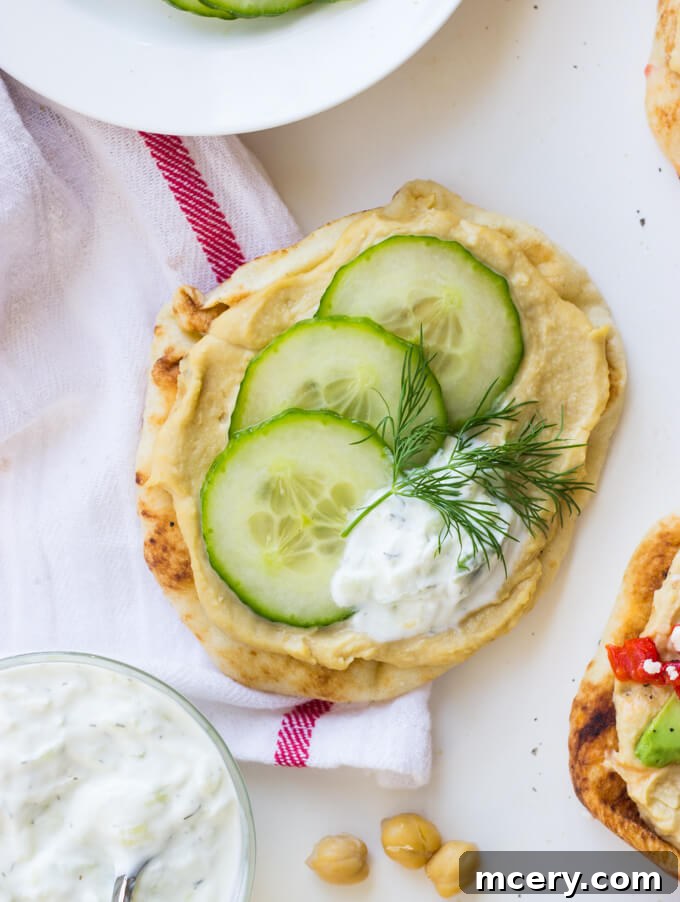 Easy Hummus Naan Toasts: 3 Delicious Variations 5 A refreshing mini naan toast featuring hummus, a generous layer of tzatziki, and thinly sliced cucumber, garnished with fresh dill.